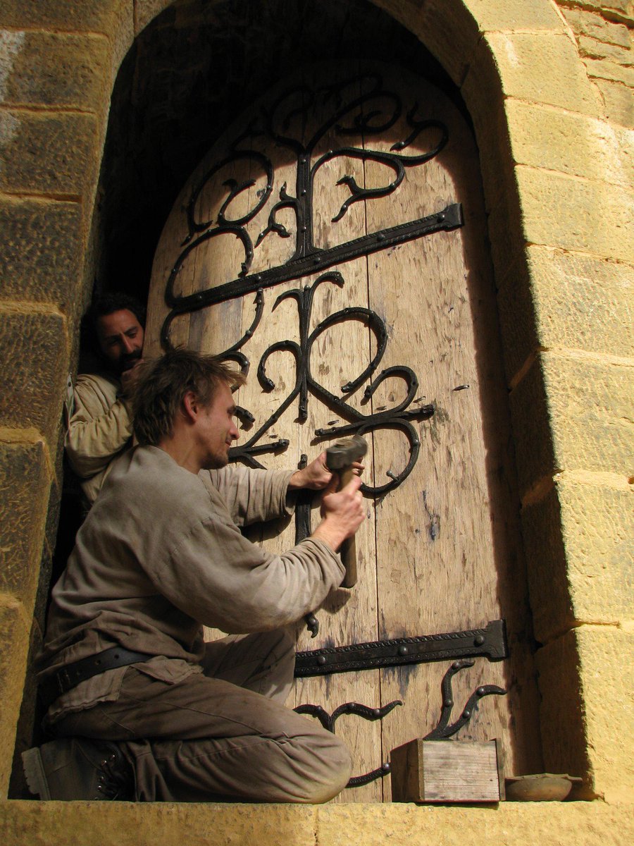 MartinClaudel's tweet photo. Guédelon's former #blacksmith Olivier Leclerc fitting strapwork to Great tower's door 2010 http://t.co/e25mLgQ3nG”