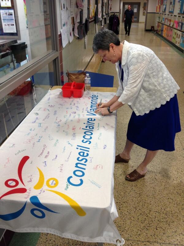 La directrice de l'éducation Gyslaine Hunter-Perreault signe le drapeau de l'ÉÉ La Mosaïque #csviamonde15ans #onfr