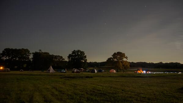 Lots of tent campers sitting around the fire at the farm campout Friday night