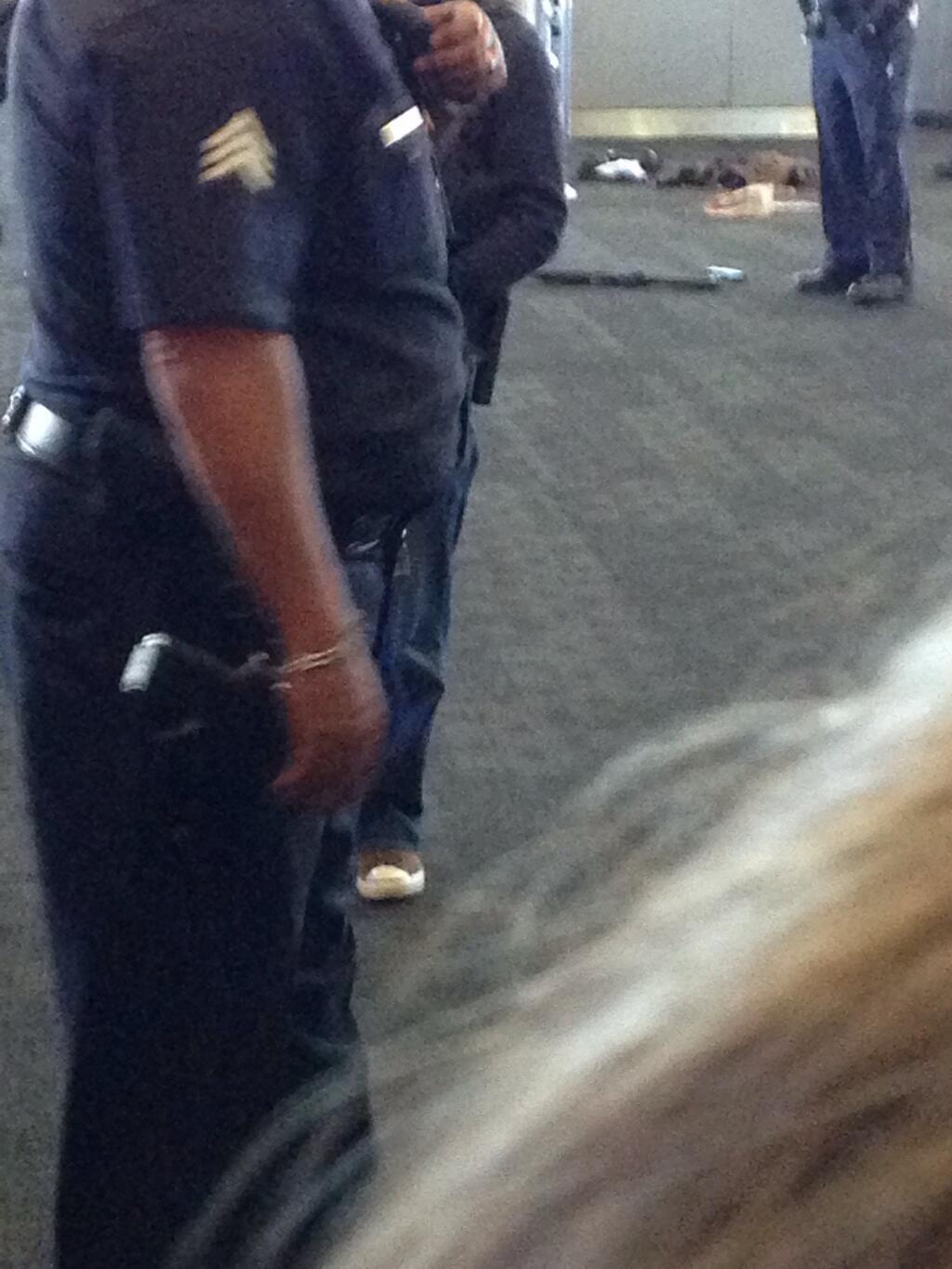 Another Picture of rifle on the floor at LAX guarded by a police  