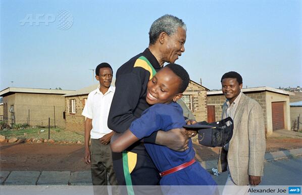 AFP's tweet photo. Photo of the day: A young girl hugs  Nelson Mandela, October 1990, in Soweto, by Alexander Joe via @afpfr  http://t.co/QfvAqpLzUJ