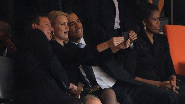Looks like Obama is continuing the funeral selfie trend at Mandela's service.  Michelle is having nothing of it.