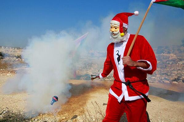 NewsBreaker's tweet photo. The Middle East: Palestinian in Santa suit runs away from Israeli tear gas canister Majdi Mohammed/AP @pourmecoffee http://t.co/ox3wbFBvr2