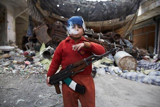HistoryInPics's tweet photo. Ahmed, the eight-year-old son of a Syrian rebel fighter, smoking and holding an AK-47 in Aleppo. http://t.co/hMmL0zv8xo