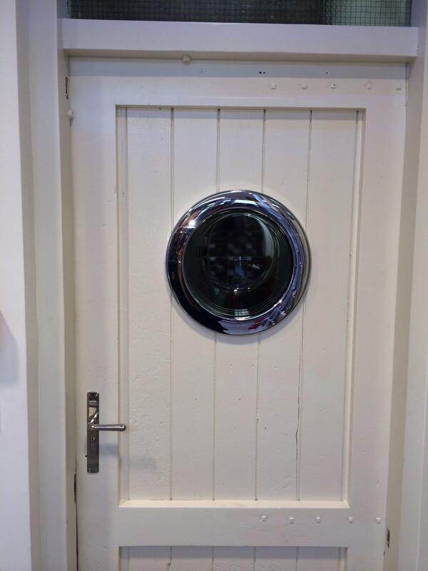 Oude wasmachinedeur doet dienst als deurspion.