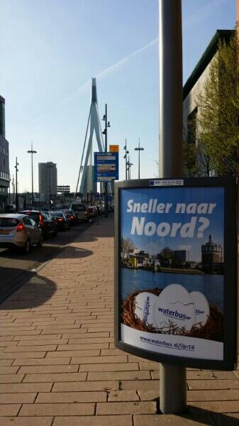 AMplusD's tweet image. Waterbuscampagne 'Nieuwe lijn 19; sneller naar de overkant!' Driehoeksborden aan de voet van de Erasmusbrug @waterbus