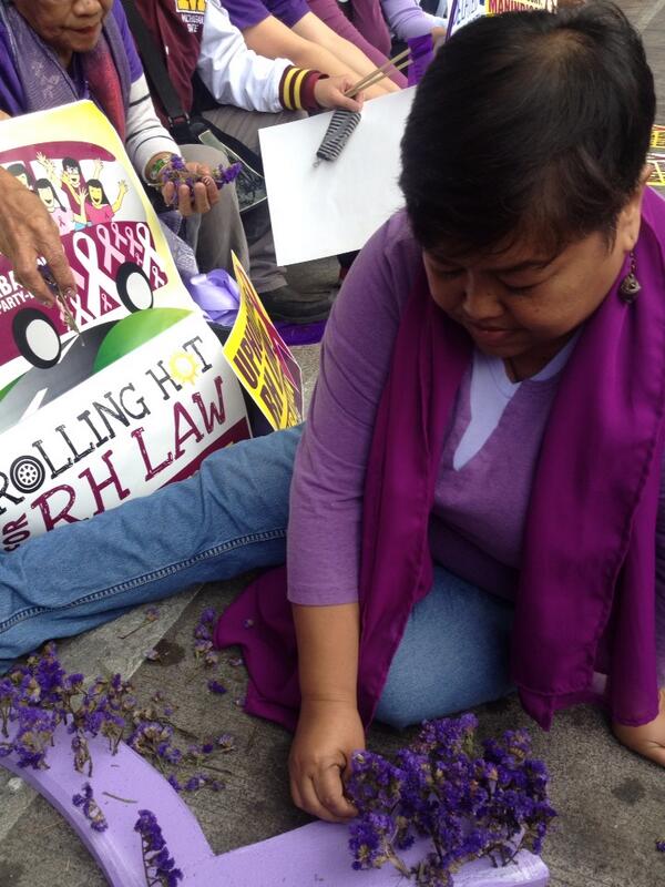 risahontiveros's tweet photo. Akbayan's Osang Palma plants Cordi statis flowers on a purple ribbon prop this morning outside the SC Baguio #YestoRH http://t.co/VCObXFgY8m