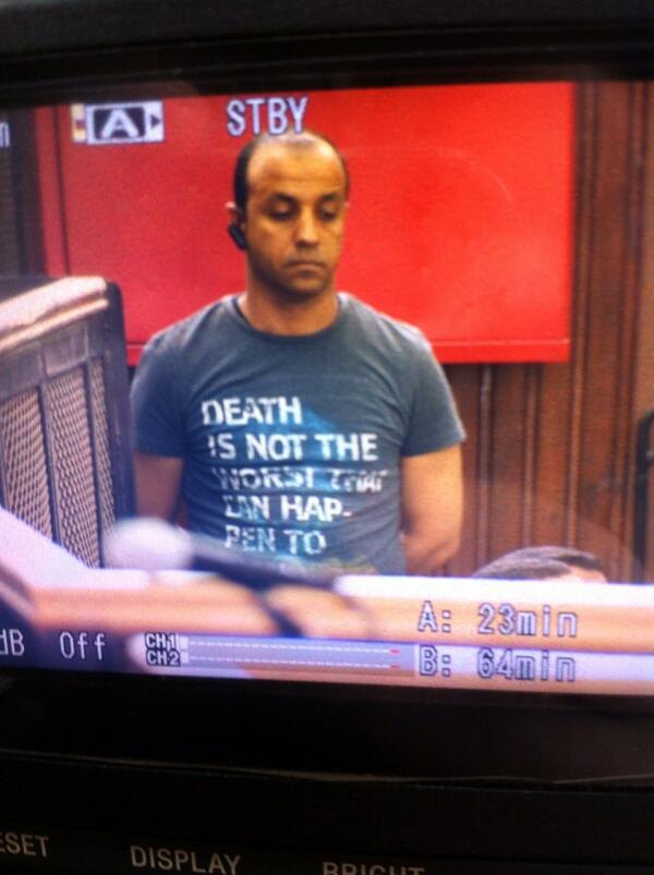 OrlaGuerin's tweet image. Photo of the man in court who opens the cages. Check out the slogan in english #AJTrial