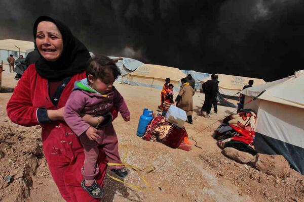 SaveSyriasChild's tweet photo. A woman carries her child to escape from the burnt tents at Zattari Syrian refugee camp near Mafraq, Syria, on March8 http://t.co/iSqBlNixRj