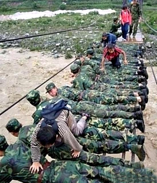 صورة معبرة لجنود صينيين يشكلون جسراً بشرياً بأجسامهم ليعبر الأطفال عليه خلال فيضانات  بدلاً من الجسر المتهالك ..!