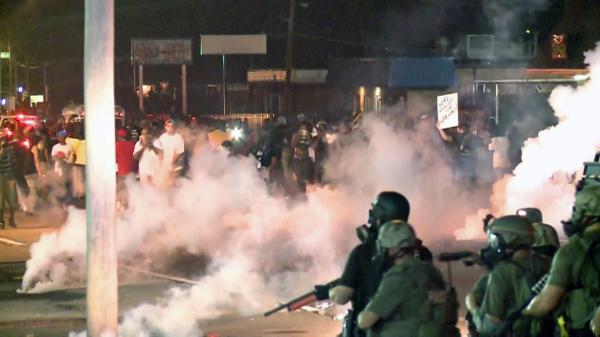 NBCDFW's tweet image. RIGHT NOW: Police are firing tear gas on protesters in Ferguson, Mo. on the second night of a state-imposed curfew.