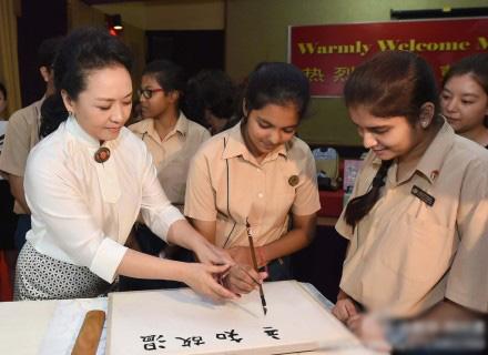 TopNewsChina's tweet photo. Peng Liyuan, wife of Chinese President Xi Jinping, teaches students to use Chinese writing brush in New Delhi http://t.co/hKMlXn98ID