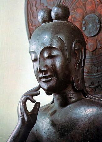 【奈良・中宮寺/菩薩半跏像(飛鳥)】双髷を結い、左足は踏み蓮華の上に載せる。丸みを帯びた体躯は女性的。瞳は彫られておらず、上瞼の下にできる影によって伏目がちに見せる。口元の両端はぼかされ、頬に自然につながるような表現技法をとる。