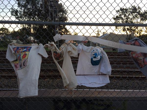 Foodscene's tweet photo. Gotta love Newtown for being weird. Free Thai tshirts hanging on a railway fence. http://t.co/Rkc547A9ff