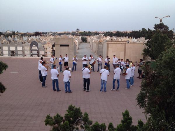 All'alba la banda di Lampedusa inizia suonando nel cimitero. "Noi suoniamo per tutti" dicono. Vivi e morti