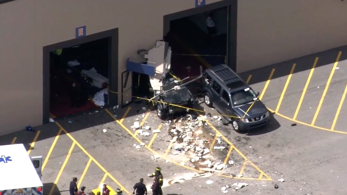 At least 2 dead, 12 injured after car crashes through auto auction in