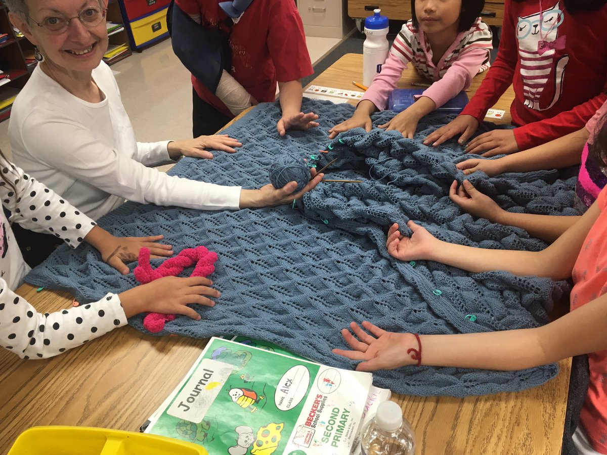 Itinerant, Carol Fisch shares her wool blanket with Ms. Buckles' second graders after reading about natural and intermediary resources.