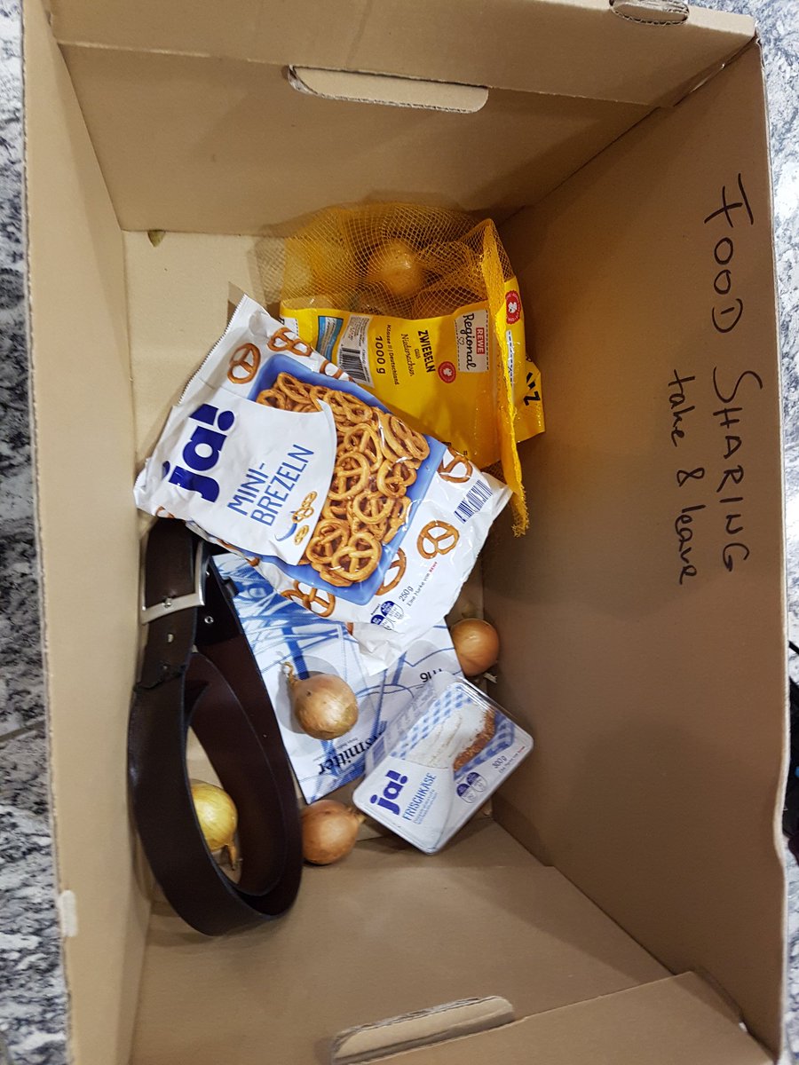A cardboard box with a few food items and a leather belt.