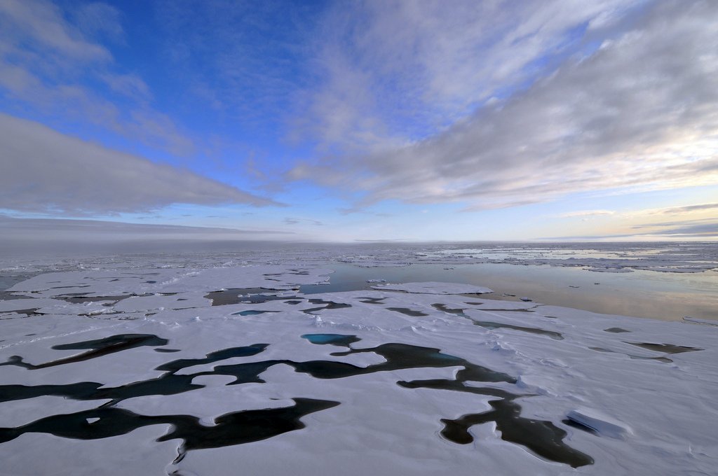 Patches of ice atop Arctic waters under a cloudy sky
