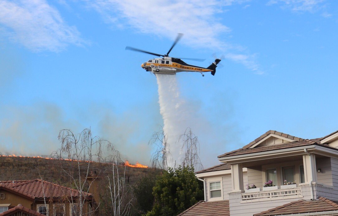 LACoFireAirOps's tweet image. Our Firehawk helicopter makes a water drop behind homes as #SageFire approaches. We assisted @VCFD @VCAirUnit with fire fight.(📷@photo_91)