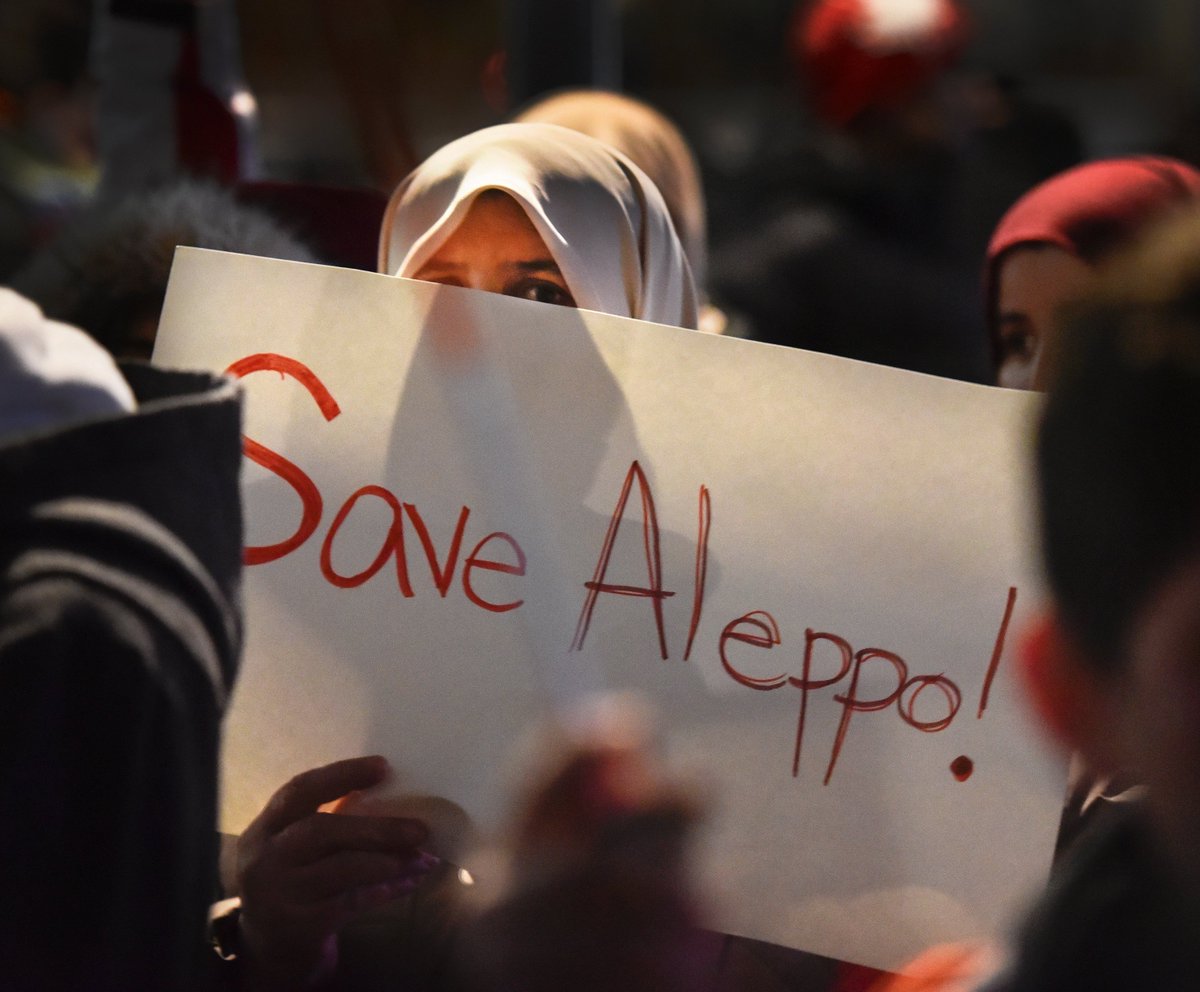 JLRenn's tweet photo. A woman holds a Save Aleppo at a solidarity rally outside #HamOnt city hall. #IStandWithAleppo https://t.co/5gjAaoe4Ni