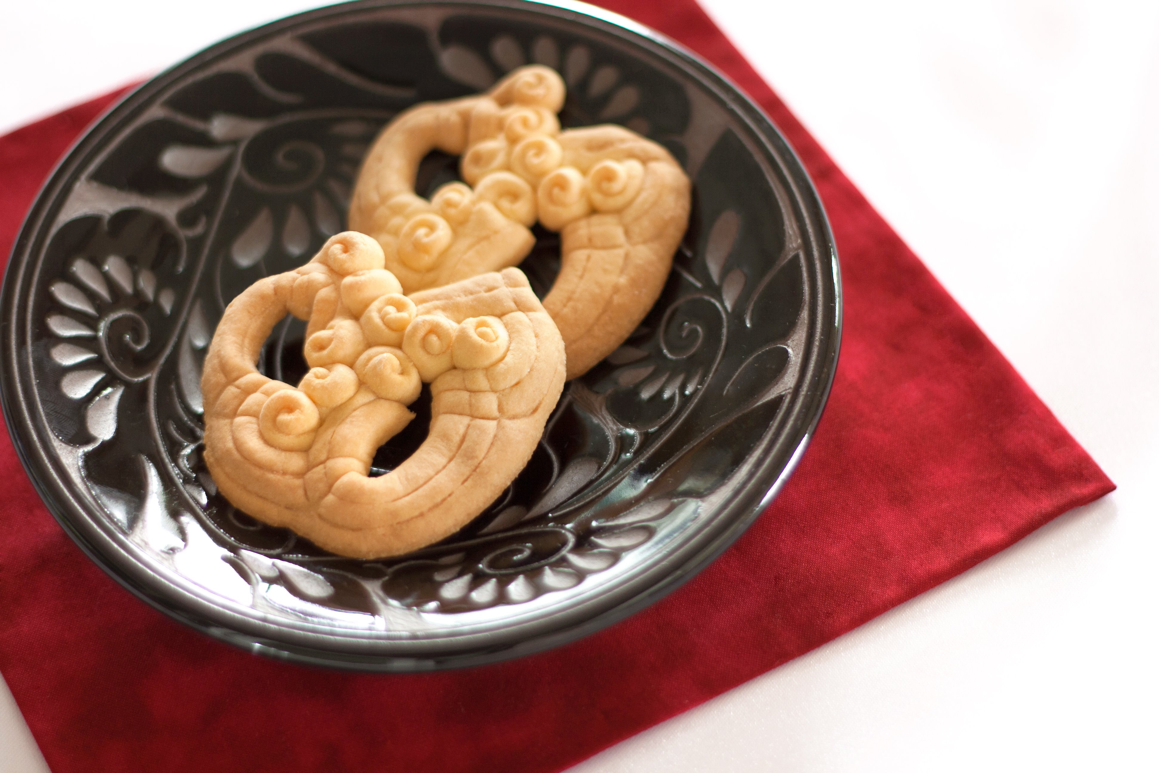 新垣ちんすこう本舗 花ぼうる は小麦粉 卵 砂糖 を使った焼き菓子です 水を使っていないので独特な触感があります 一枚一枚 職人が丁寧につくってます 藤の花の形 をイメージしておりますが 店頭では シーサーの形ですか と聞かれるお菓子です