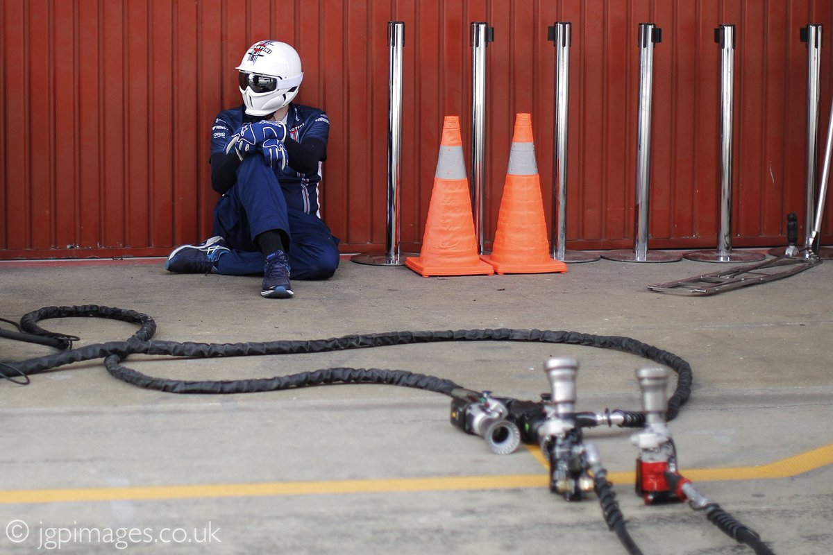 A <a href="/williamsf1/"></a> mechanic sits in the pit lane while waiting for pit stop practice at <a href="/Circuitcat_eng/">Circuit de Barcelona-Catalunya</a> during the #F1 pre-season test.