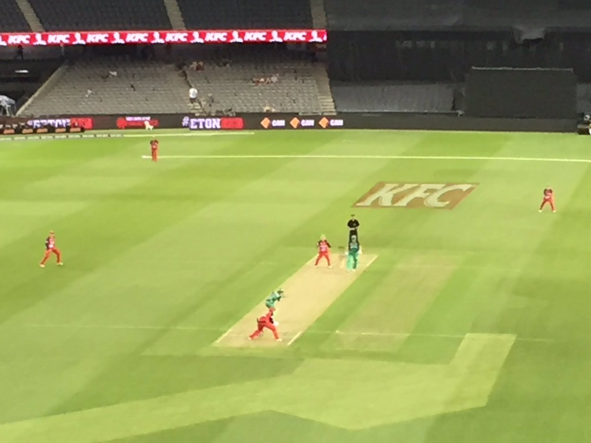 Very distant view of cricket pitch with Katie Mack batting