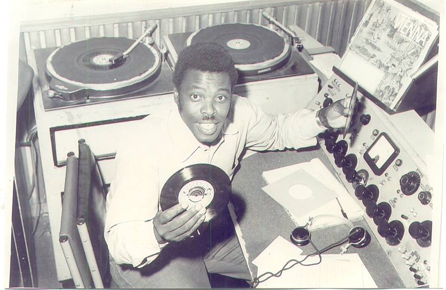 A radio presenter holding a record disk. Mambo Mbotela