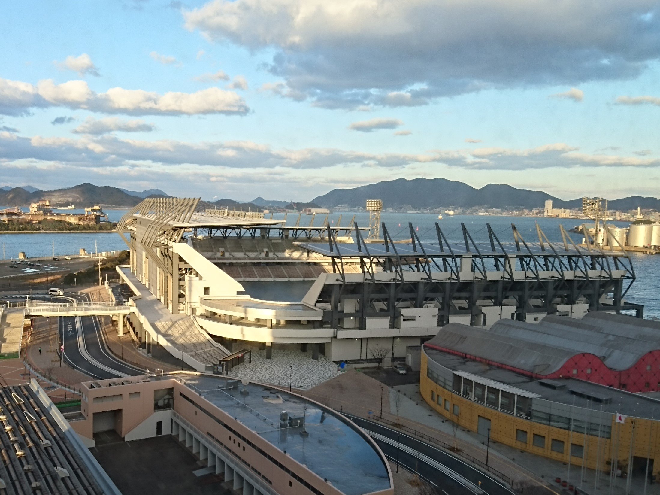 南博 本日1 24夕方のミクニワールドスタジアム北九州 北九州スタジアム 建設現場 ピッチ部分は芝生養生シートらしき物で一面覆われ黒く見える 夕焼けに映える姿も美しい 2 18プレオープン ラグビー試合 まで25日 3 12グランドオープン サッカーｊ３