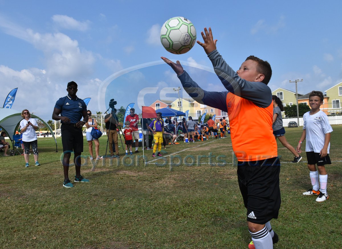 CaySportsBuzz's tweet photo. Monday's #BuzzShot from Academy Sport's Club Mini Slam. A young goalkeeper participates in drills conducted by Dwight Yorke, who looks on. https://t.co/ZIgW0XoOJe