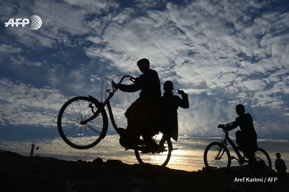 Afghanistan - Boys ride their bikes along a road during sunset on the outskirts of Herat. #AFP by <a href="/Arefkarimi/">Aref Karimi</a>