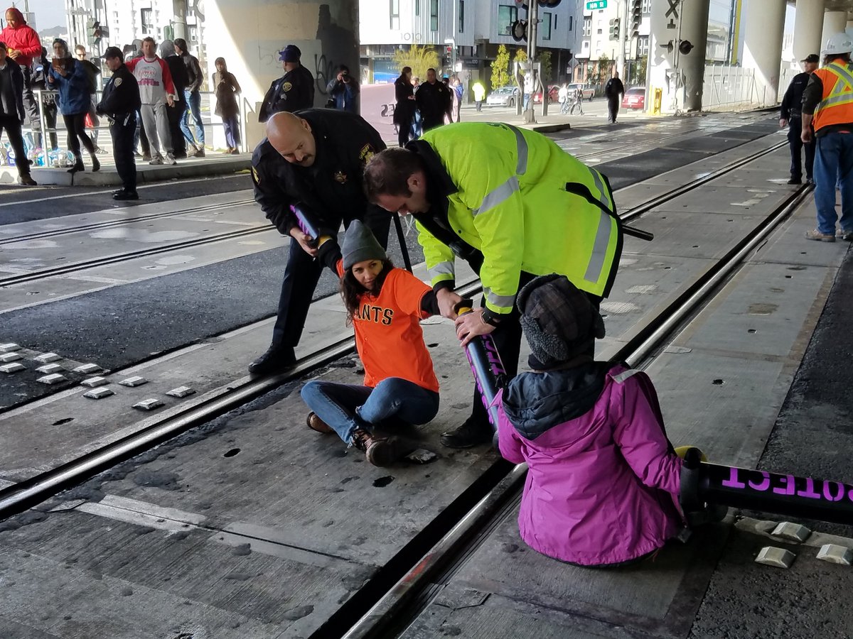 Indybay's tweet photo. After one protester is arrested, another runs in and locks down to take her place.
#J20 #120Hours #ReclaimMLK #Ungovernable https://t.co/c0rTD4XbVh
