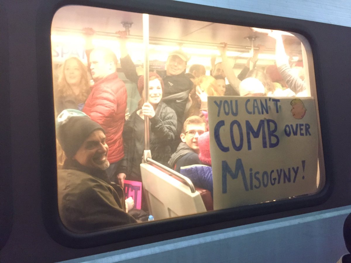 reemadamin's tweet photo. Trains into the city are packed, but everyone's smiling. #WomensMarch #hrwomen https://t.co/tifPaCg4ds