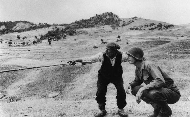 1943, Un aldeano siciliano indicando a un soldado estadounidense por dónde se han ido los alemanes