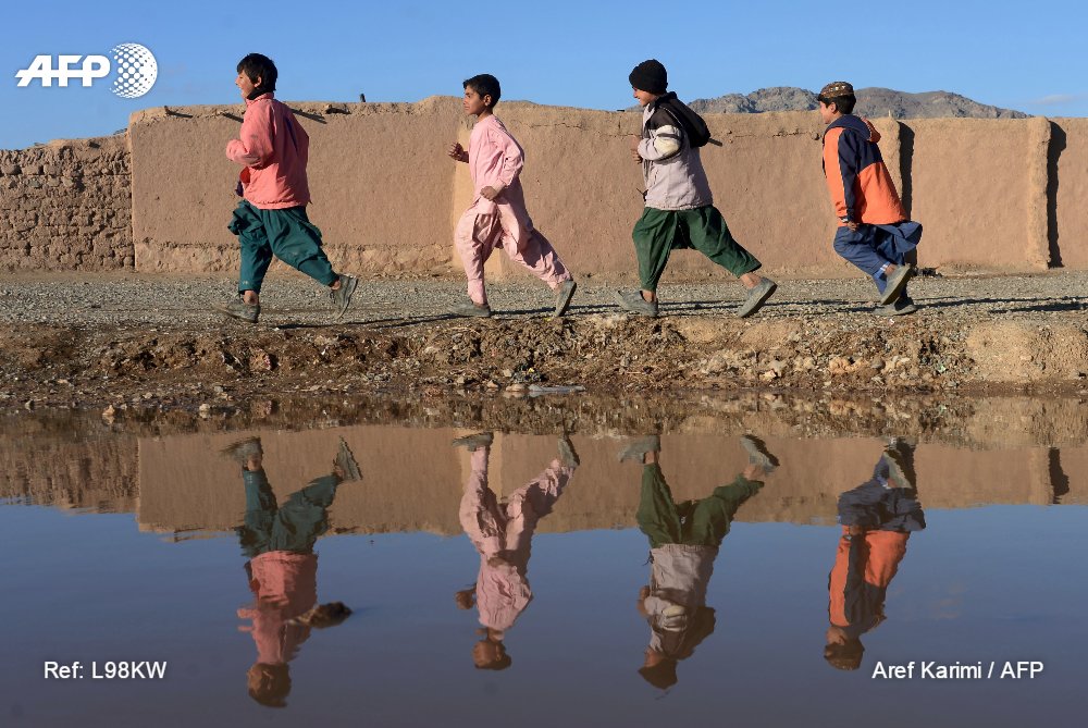 Afghan youth are reflected in a pool of rainwater on the outskirts of Herat, on January 30. #AFP by <a href="/Arefkarimi/">Aref Karimi</a>