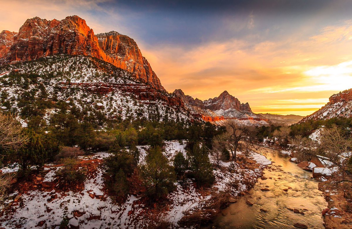 Golden light on snow-covered red rock formations and a flowing river
