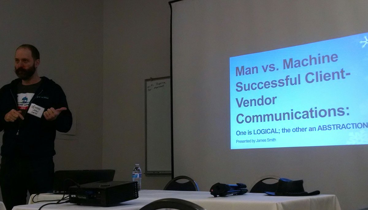 James Smith standing in front of a screen that says Man vs Machine