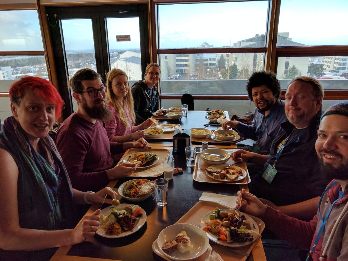 7 people around a table with trays of food, iceland skyline in background