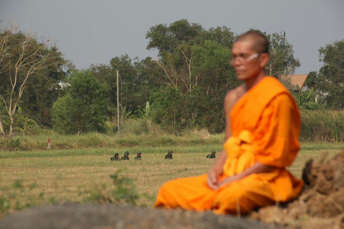 pparamai's tweet photo. A monk meditating while a group of soldiers crawling through grass: They are protecting him? I'm not sure #Dhammakaya #humanrights #Buddhism https://t.co/t8Ilo3xGNl