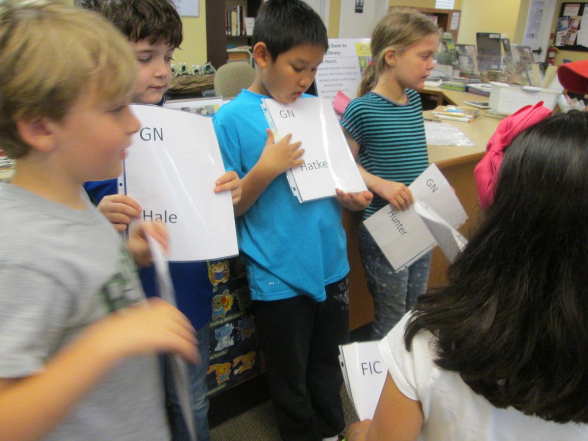2-3 students hone their mad skills by sporting spine labels and lining themselves up on a "shelf" in order. #LoveMyJob <a href="/HighMeadowsGA/">High Meadows School</a>