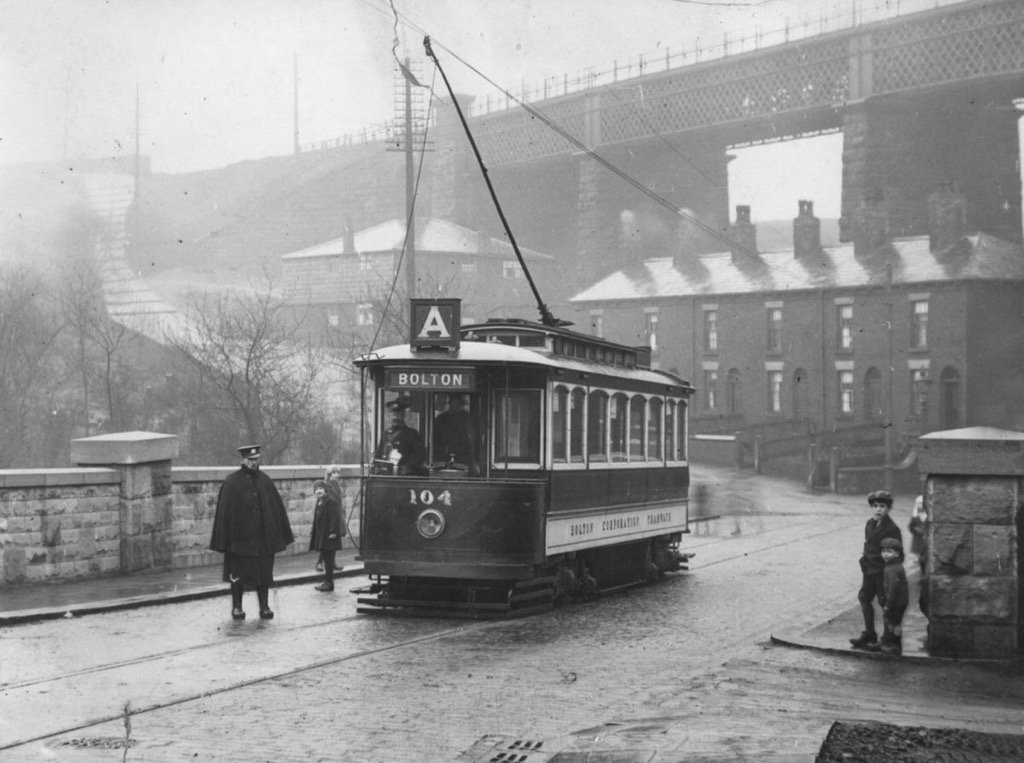 Number 104, a pre 1914 2 axle single deck Bolton Corporation tram on route A in poor weather. Little Urchins observe