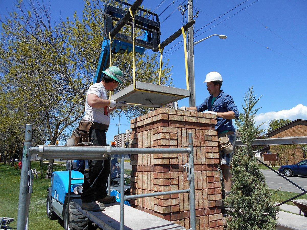 Rebuilding #brick columns. Action shot of the guys installing a large #concrete cap #brickrestoration #brickrepair #masonryrestoration
