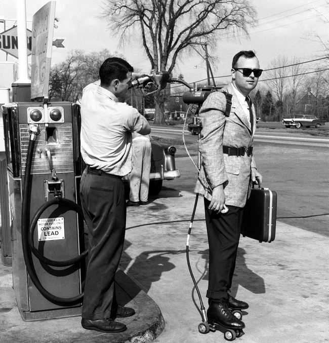 A salesman has his motorized roller skates refueled at a gas station (1961)