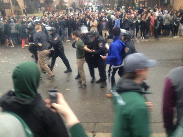 ChadLivengood's tweet photo. Here's a better action shot of the crowd dispersing and cops detaining some of the revelers. #MSU #EastLansing http://t.co/1SdDch4FLj