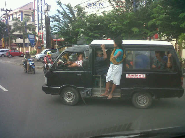 Kenek angkot Perempuan bergelayutan d pintu angkot, salah satu sisi emansipasi. ( Foto by: Umam Tim LiveU SBOtv )