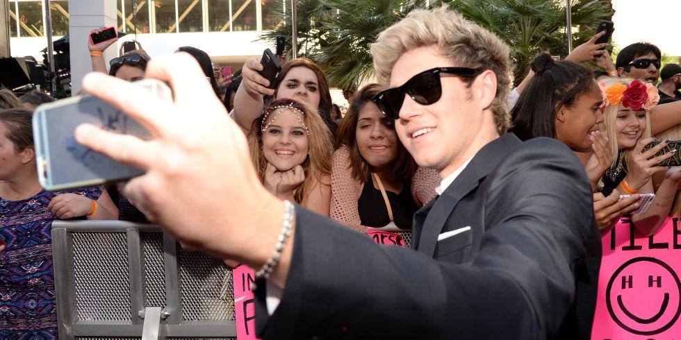 Niall Horan at the Music Billboard Awards wearing Ray Bans, taking a selfie with fans