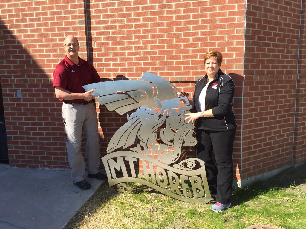 Peter &amp; Kelly Nelles present a gift of a solid stainless steel Viking logo outside of the new fitness center.