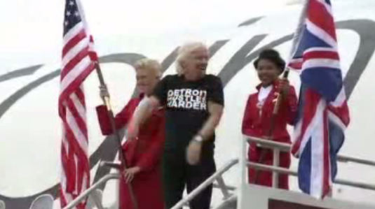 Local4News's tweet photo. PICS: @richardbranson steps off new #Detroit @VirginAtlantic flight wearing "Detroit Hustles Harder" shirt. http://t.co/bJpw3Tc5nM