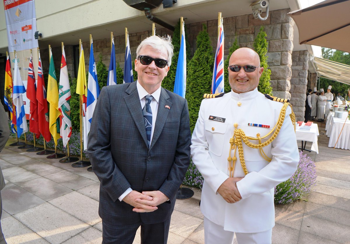 CanEmbTurkiye's tweet image. Ambassador John Holmes and Navy Captain Ivan Allain posing next to the provincial flags for #CanadaDay2015